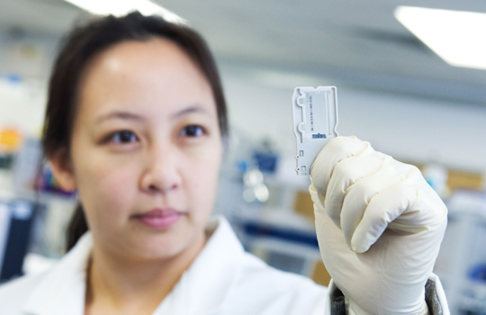 Next generation sequencing (NGS) laboratory scientist studying a FlowCell.