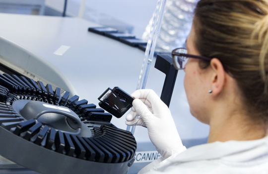 Array comparative genomic hybridization (aCGH) laboratory scientist loading a sample slide.
